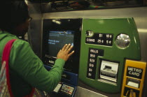 Young woman using metro ticket machine to purchase ticket.