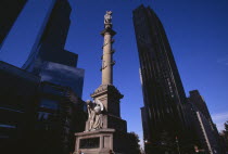 Columbus Circle.  Marble statue of Columbus on granite column decorated with bronze reliefs and angel holding globe at pedestal.  Times Warner building in background.Erected to commemorate the 400th...