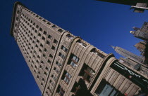 Angled view of the Flatiron Building from 23rd Street.  Steel framed  Beaux-Arts skyscraper designed by architect Daniel Burnham in 1902 to a triangular plan.