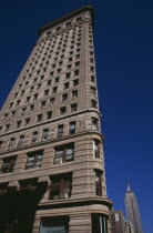 Part view of the Flatiron Building from 23rd Street.  Steel framed  Beaux-Arts skyscraper designed by architect Daniel Burnham in 1902 to a triangular plan.