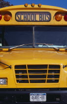 Cropped shot of bright yellow front bumper  windscreen and number plate of school bus.