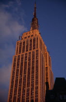 Part view of the Empire State Building from 7th Avenue / West 31st Street.  Art Deco  steel framed building with radio and TV mast completed in 1931. Deep orange light. Designed by architect William...