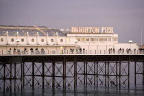 Close-up of mid-section of Palace Pier at sunset with people walking along it