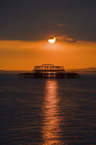 Remains of the West Pier silhouetted against an orangy-red sun setting