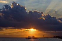 Dramatic orange sunset silhouetting remains of the West Pier