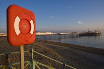 Shingle beach with Brighton Pier and the English Channel in the background and bright-red life-saving equipment in foreground