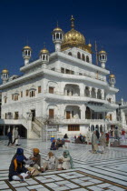 The Sri Akal Takhat Sahib Sikh Parliment building in the Golden Temple with groups of people gathered outside