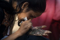 Participant in the Mehendi competition at the Alwar Utsav Festival applying an intricate henna design onto the palm of her hand