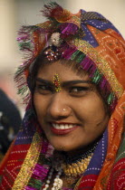 Portrait of a female dancer smiling wearing a multi coloured head dress at the Alwar Utsav Festival