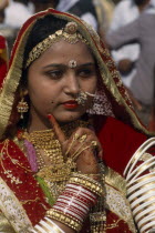Portrait of a Miss Desert contestant with henna painted hands  finger resting on her cheek. Wearing red and gold with traditional jewellery at the Desert Festival