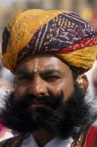 Head and shoulders portrait of a Mr Desert contestant with a beard wearing a colourful turban at the Desert Festival