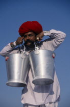 Rajput man lifting buckets of water with his moustache during the Camel Festival.