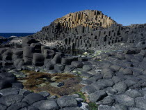 Interlocking basalt stone columns left by volcanic eruptions. View across the main and most visited section of the causeway with the coastline seen behind.