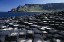 Interlocking basalt stone columns left by volcanic eruptions. View across the stones towards the east from the main section with cliffs and coastline