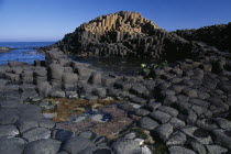 Interlocking basalt stone columns left by volcanic eruptions. View across the main and most  visited section of the causeway with the coastline seen behind.