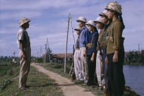 Line of male and female Viet Cong soldiers standing in front of superior officer