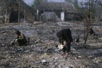 Woman trying to salvage items in bombed residential area.