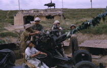 Members of Militia unit  not regular army with anti-aircraft missile launcher.  Child riding water buffalo on crest of hill behind.