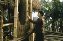 Young woman using bomb casing as an air raid warning device.