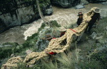 Men from the Chumbivilcas hills carrying length of thick rope made from woven bunch grass to make main cable or trense used for bridge construction by local villagers.