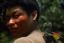 Portrait of young Campa tribesman with red and black painted face looking towards camera over his shoulder.