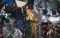 Women at standpipe carrying pails of clean water on their heads.  Following 1994 cholera outbreak an urban health programme was set up to teach health awareness.