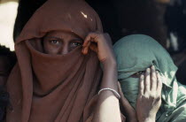 Head and shoulders portrait of two Beja nomad Arab girls  veiled so that only their eyes are visible.