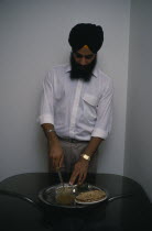 Sikh man using short knife or kirpan to bless food.