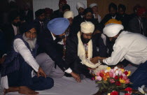 Groom receiving gifts from guests during wedding ceremony.