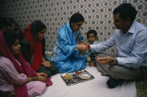 Woman tying thread on wrist of man during the Sacred Thread ceremony. The Hindu male rite of passage ceremony