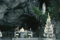 Lourdes.  Priest conducting service at cave shrine in pilgrimage centre.