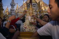 People making offerings of flowers and water at shrine in Shwedagon Pagoda.