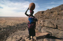 Dogon woman returning to Tirelli village with empty pot carried on her head.