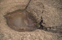 Man carrying bowl of water up steps from waterhole to irrigate his onions.