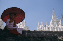 Buddhist Nun sat on a wall with umbrella at Mingun ancient city.