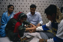 Sacred thread is fastened at the wrist of adolescent boy during Hindu male rite of passage.