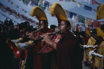 Monks of the Gelug pa sect proceed a photograph of the Dalai Lama playing shenai horns.