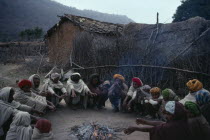 Village elders in conference seated in circle around fire.