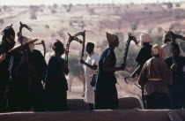 Dogon rooftop dancers brandishing carved wooden staffs a symbol of a particular Dogon fraternity.