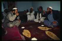 Pashtun men eating traditional meal of bread and yoghurt.