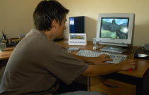 Teenage boy using computer to play game.