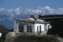 The Restaurant At The End Of The Universe with three men sitting on the roof surrounded by snow capped mountain peaks