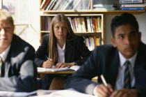 Male and female pupils working at desks in a classroom.