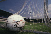 Close up of a football in the net at the back of the goal