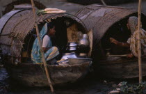 Two female river gypsies in covered wooden boats talking to each other.