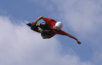 Skate boader twisting in mid air  blue sky behind.