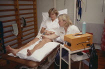 Female sport physiotherapist using ultra sound treatment on female patients leg