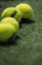 Detail of luminous tennis balls on lawn.