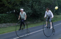 Man and woman riding old Penny Farthing Bicycles