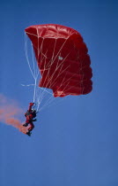 Parachutist with red garments  red Parachute and with red smoke coming from his boots.